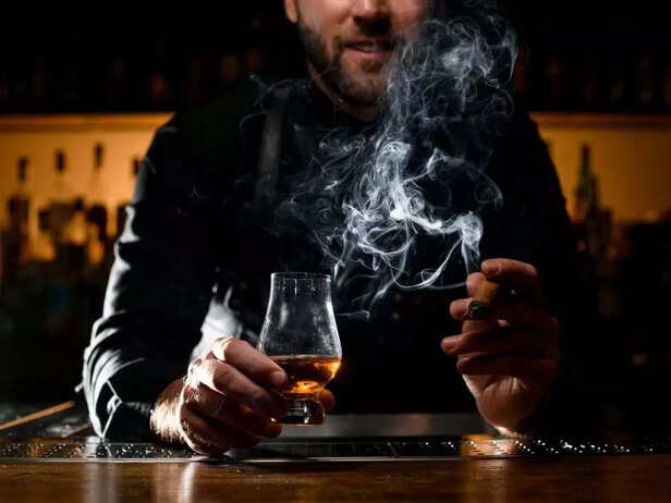 A MAN WITH A DRINK AND CIGAR