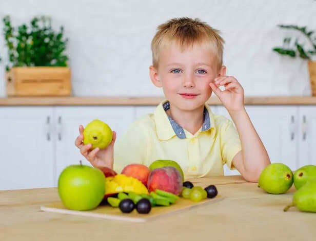 Happy little boy eating fresh fruits