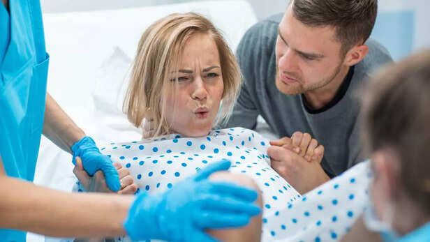 In the Hospital Woman in Labor Pushes to Give Birth, Husband Holds Her Hand for Support