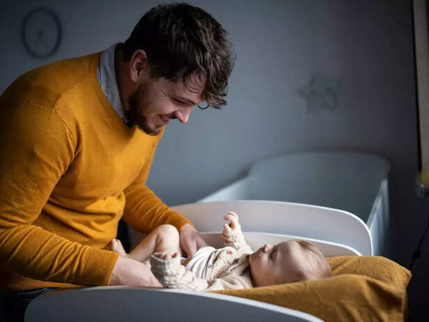 father helping child change diaper