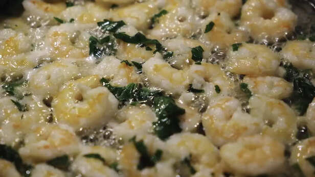 Close-up of fresh shrimps with basil fried in oil on a frying pan. Concept. Delicious seafood