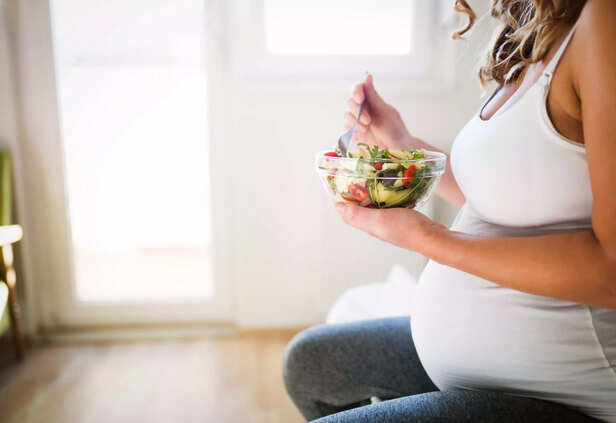 Beautiful pregnant woman eating healthy food and salads