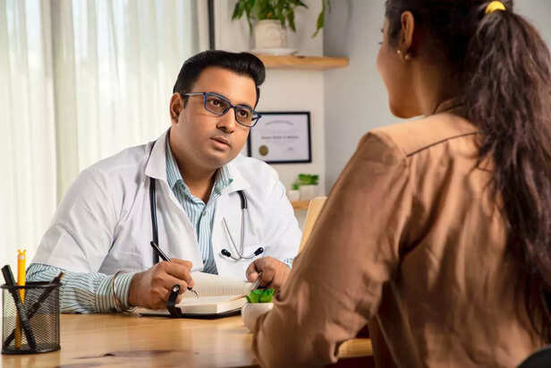 Male Doctor in a medical clinic writing prescription for a young female patient.