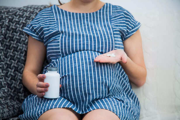 Close-up Of Pregnant Woman Hand With Vitamin Pills
