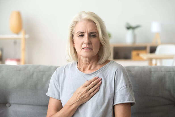 Upset stressed mature older woman feeling heartache touching chest