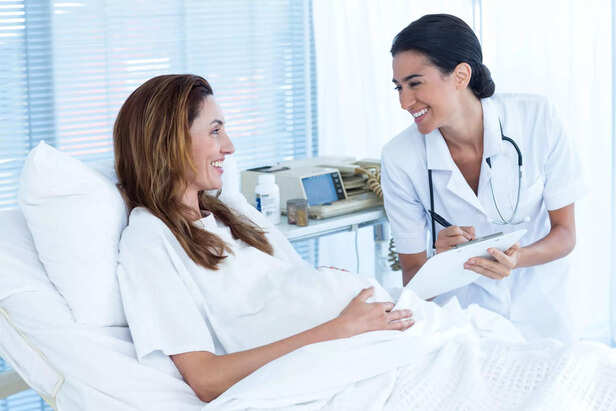 PREGNANT WOMAN DISCUSSING THE BABY'S MOVEMENT WITH HER DOCTOR