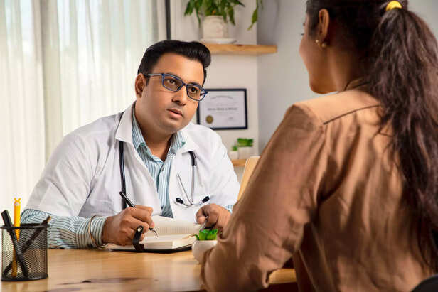 Male Doctor in a medical clinic writing prescription for a young female patient.