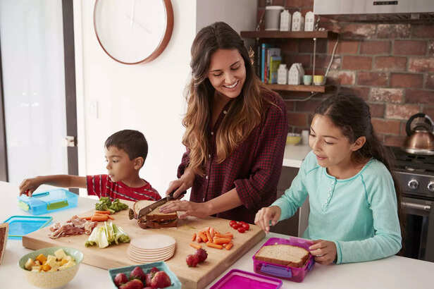 Children Helping Mother In Kitchen At Home
