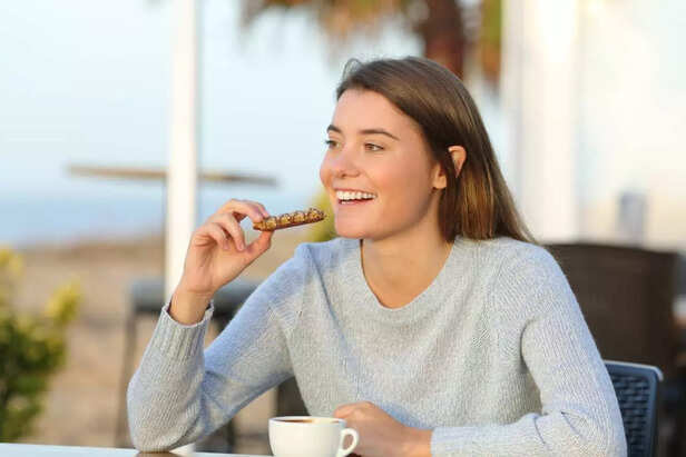 Happy girl eating a snack in a cafe terrace