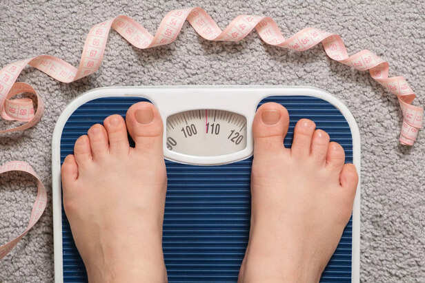 Women's bare feet on floor scales and measuring tape, weight 100-110 kilograms, top view. The idea of obesity, weight loss and excess weight.