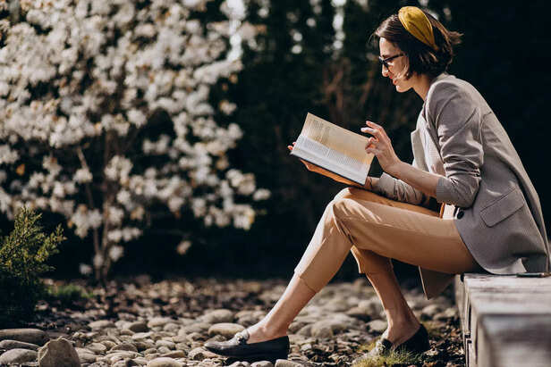 young-woman-sitting-backyard-reading-book