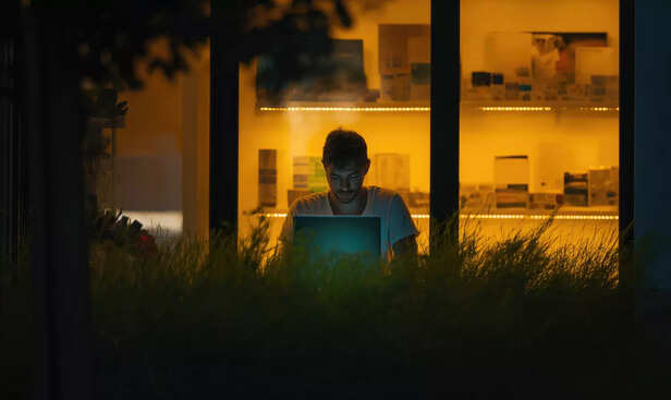 A young man alone on a balcony at night,