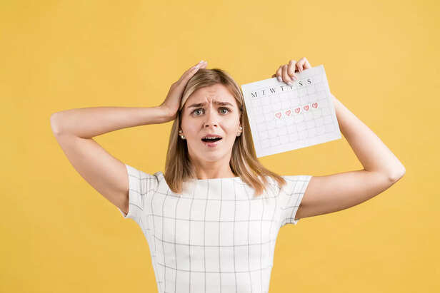 "Confused Woman Holding Menstrual Calendar with Marked Dates on a Yellow Background