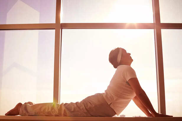 A woman doing light yoga near a sunny window