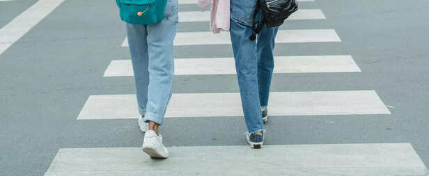 Women wearing jeans crossing city street