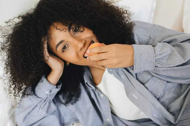 A woman eating a peach
