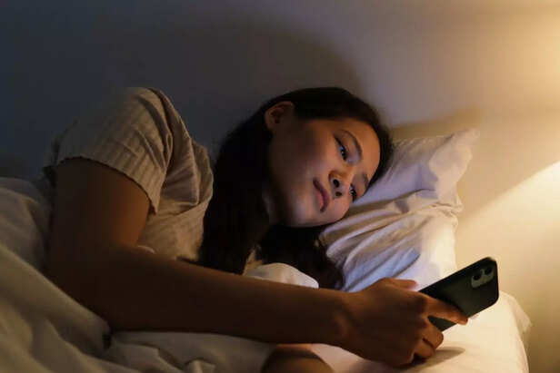 Woman using phone in bed