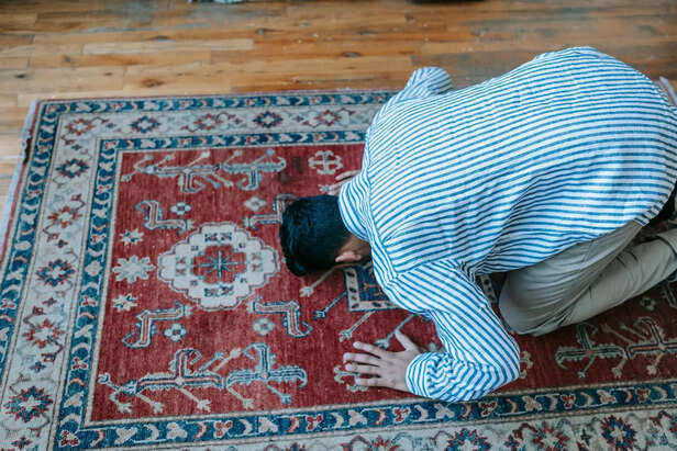 Man Bowing Down on Red and Blue Area Rug