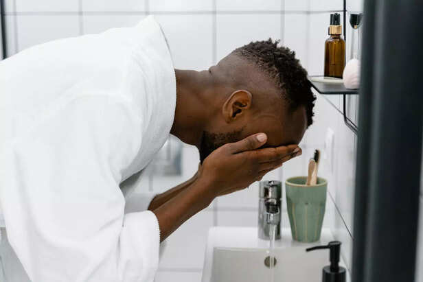 Man in White Robe Washing His Face