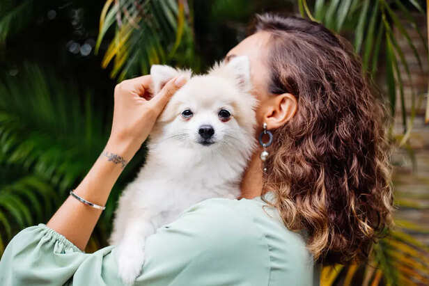 Woman Holding a Cute Pomeranian Dog Outdoors