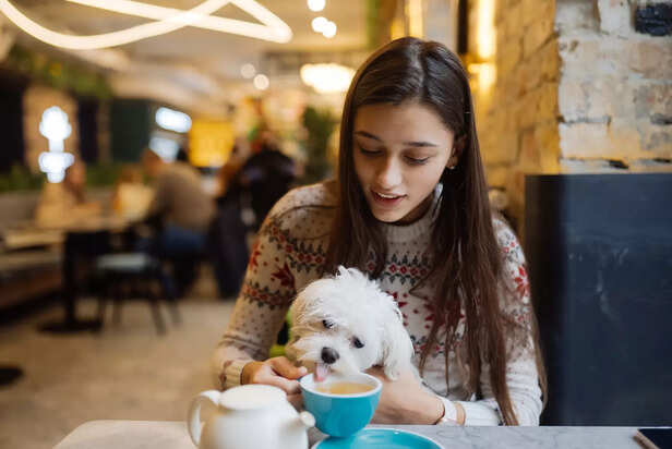 woman holding her cute dog &amp; drinking coffee