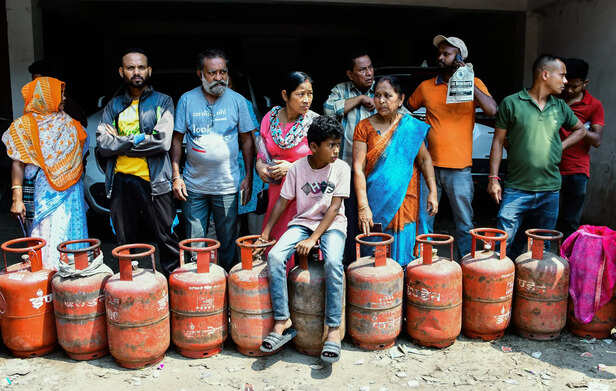 People stand in a long queue with their LPG cylinders ou...