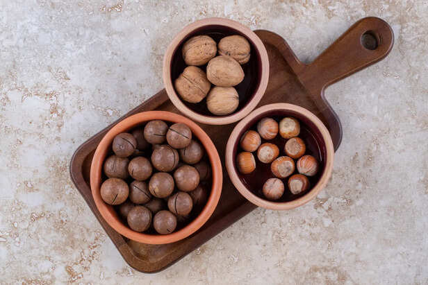 Shikakai, amla, and reetha arranged in wooden bowls