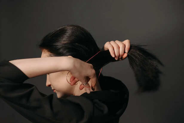 Person Gently Stretching a Strand of Hair