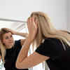Young adult noticing grey hair in the mirror