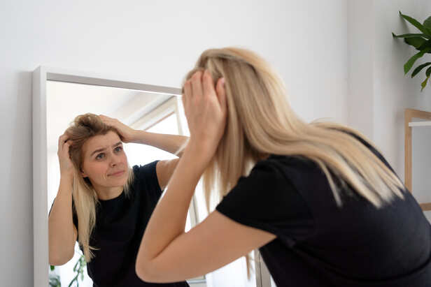 Young adult noticing grey hair in the mirror