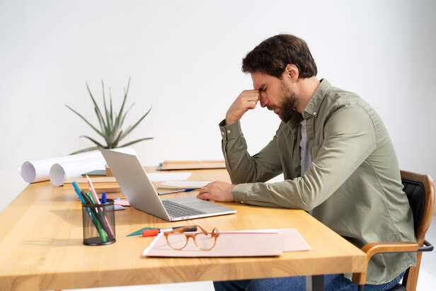 Person feeling exhausted while sitting at a desk