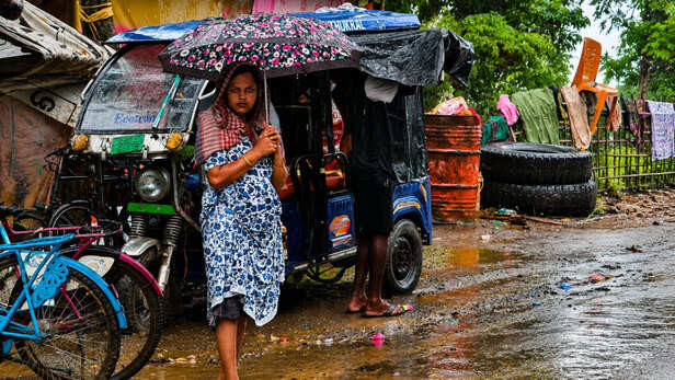 मूसलाधार बारिश के बीच सड़क किनारे सुरक्षित ठिकाने की तलाश कर रही महिला