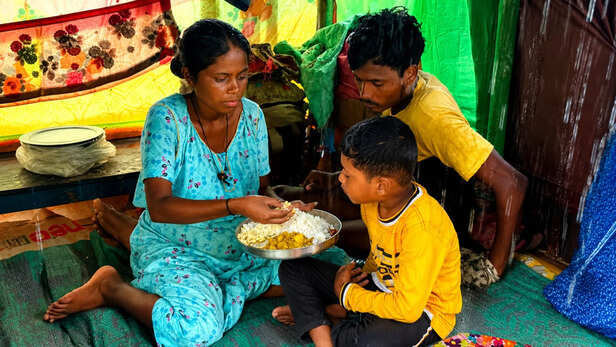 बारिश के बीच अस्थायी ठिकाने में भोजन करता परिवार