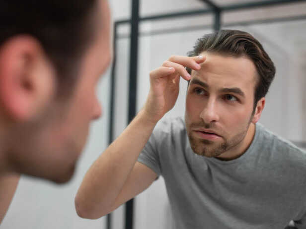 Person noticing thinning hair in the mirror