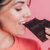 Woman enjoying a small piece of dark chocolate