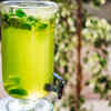 Fresh green amla beside a glass of juice