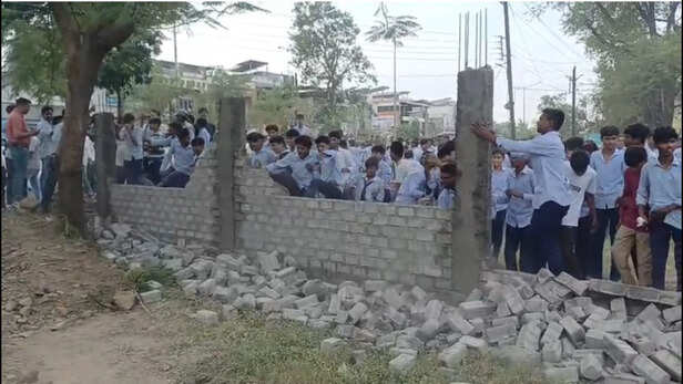 बाउंड्रीवाल तोड़ते हुए छात्र